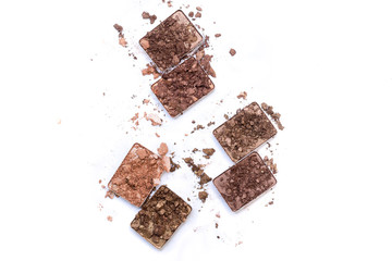 Broken make up and cosmetic products. Smashed eye shadow palette in neutral colors isolated on white background.