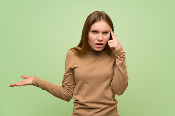 Young woman with turtleneck sweater making the gesture of madness putting finger on the head