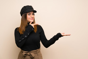 Fashion woman with hat holding copyspace imaginary on the palm to insert an ad