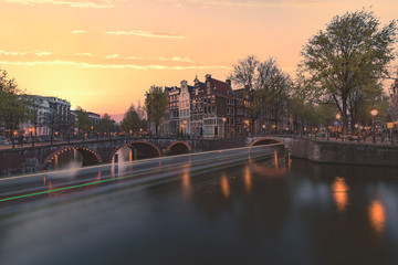 Long exposure boat cruising along the Amsterdam calm canal at the blue sunset hour, Netherlands