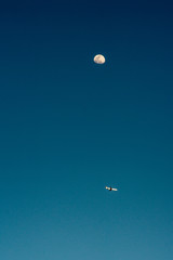 airplane on a blue sky on the background of the moon