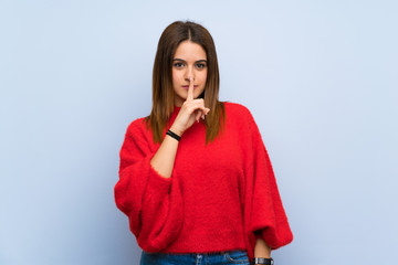 Young woman over isolated blue wall showing a sign of silence gesture putting finger in mouth