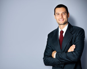 Happy businessman with crossed arms, on grey