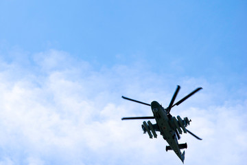 Russian military combat attack helicopter K-52 Alligator flies against a blue sky and clouds