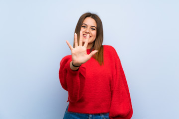 Young woman over isolated blue wall counting five with fingers