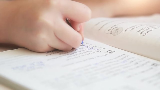 Girl sitting at the table writing in a notebook homework in English HD 1920x1080