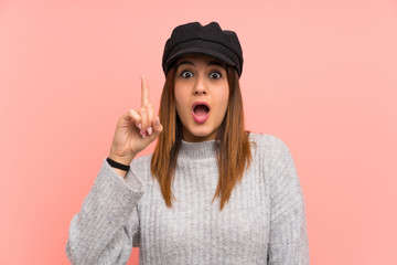 Fashion woman with hat over pink wall with surprise facial expression