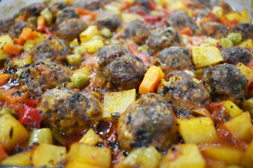 on marble floor, meatballs with vegetables, in glass baking dish