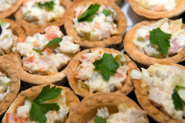 Fish and meat salads in tartlets on a plate.