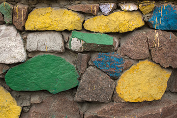 Foundation but stones painted in different colors. Construction rubble wall close up