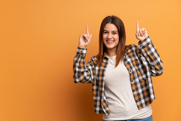 Young woman over brown wall pointing up a great idea