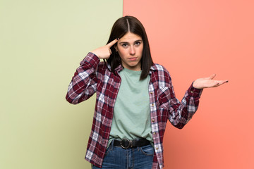 Young woman over isolated colorful wall making the gesture of madness putting finger on the head