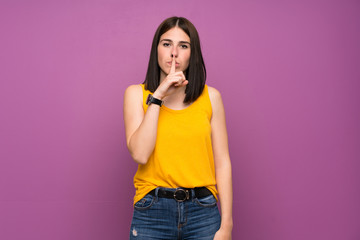 Young woman over isolated purple wall showing a sign of silence gesture putting finger in mouth
