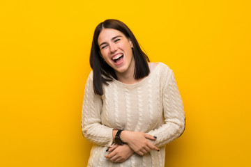 Young woman over isolated yellow wall smiling a lot