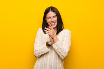 Young woman over isolated yellow wall applauding after presentation in a conference