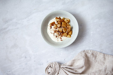 Baked apple with cinnamon and vegan coconut yogurt in rustic plate on marble background with copy space