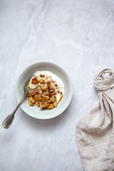 Baked apple with cinnamon and vegan coconut yogurt in rustic plate on marble background with copy space