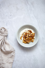 Baked apple with cinnamon and vegan coconut yogurt in rustic plate on marble background with copy space
