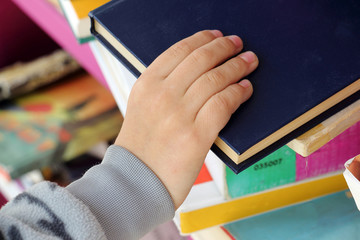Kid's Hand Taking Book from a Shelf in Public Library