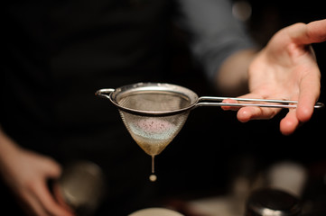 Close-up of bartender pouring cocktail using sieve