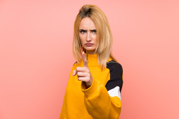 Young blonde woman over isolated pink background frustrated and pointing to the front