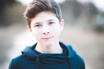 Smiling kid boy 13-14 year old wearing hoodie outdoors. Looking at camera.
