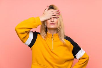 Young blonde woman over isolated pink background covering eyes by hands. Do not want to see...