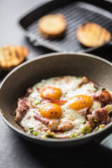 English breakfast fried bacon ham and eggs in ceramic pan