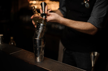 Bartender pouring cocktail adding sour mix in a shaker