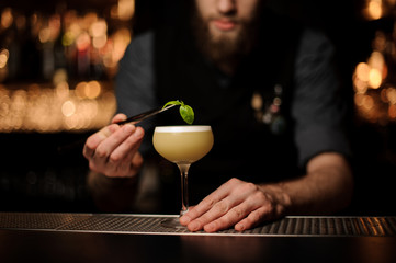 Close-up of bartender pouring cocktail using forceps