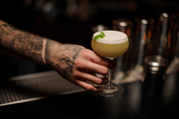 Bartender holding an alcohol cocktail in his hands