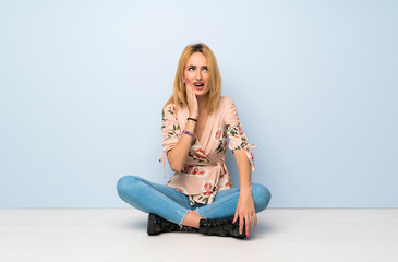 Fototapeta na wymiar Young blonde woman sitting on the floor with toothache