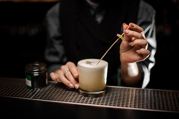 Bartender pours cocktail and adding ingredients with toothpick