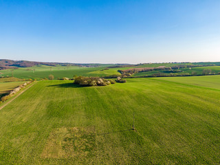 Fototapeta na wymiar Aerial view of agriculture land. Fields and meadow during sunny summer day. Trees and bushes on agriculture green land. Fresh green fields