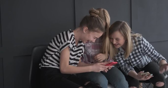 Joyful teen girls enjoying media content on mobile phone