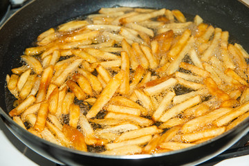 Fried french fries in a pan in sunflower oil.