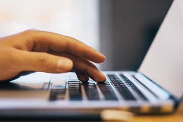 Sideview of male using laptop on desktop
