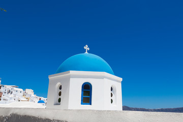 Fototapeta na wymiar Santorini, Greece - July 07, 2017: Blue dome of church close-up in island Santorini. Background white houses and blue sea.