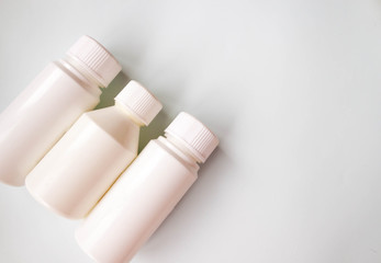 White plastic medicine pills bottle container set. Drugs, diet, nutritional supplements bottle on light blue background. Parmaceutical medicine concept. Selective soft focus, text copy space.