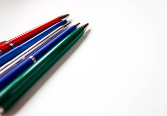 row selection of assorted multi colored ballpoint pens of different colors on light blue background. Back to school creativity concept. Selective focus, text copy space.