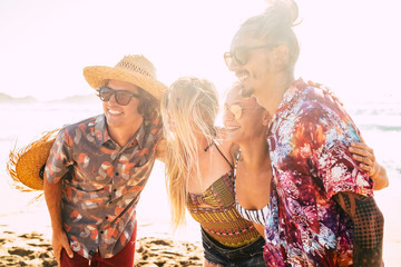 Group of cute friends people hug together and pose for a picture smiling - cheerful pretty girls and boys youthful concept for summer vacation at the beach - bright sun in backlight - friendship