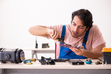 Young male contractor repairing computer  