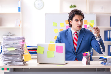 Young male handsome employee in conflicting priorities concept 