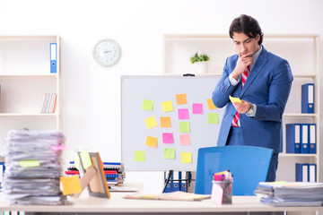 Young male handsome employee in conflicting priorities concept 