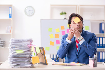 Young male handsome employee in conflicting priorities concept 