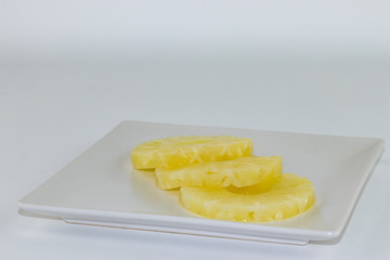 Tre fette di ananas su un piatto bianco