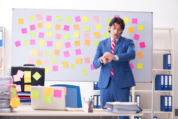 Young male handsome employee in conflicting priorities concept 