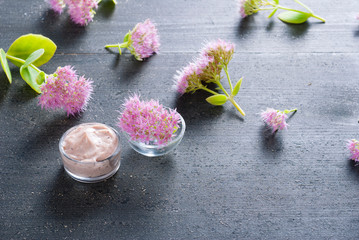 Obraz na płótnie Canvas moisturizer with pink flowers on old black wood table