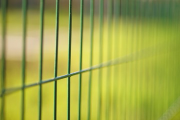 grid of green fence mesh on the background of the lawn field