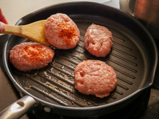 Cooking burgers on a frying pan.